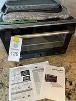 Front view of oven on countertop with MaxSold tag and manual below