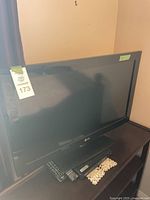 Wide view of LG 31 inch TV with two remotes and Blu-ray player on a dark wooden surface