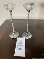 Two Oleg Cassini silver filled crystal candlestick holders on a dark surface with auction label number 349 visible.