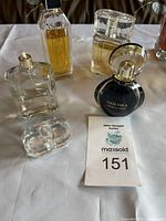 Five assorted perfume bottles displayed on white cloth including Daisy Eau So Fresh by Marc Jacobs and Goldea The Roman Night.