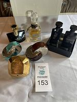 Seven perfume bottles and body products arranged on white cloth, showing brand and style details