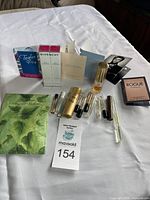 The full lot spread out on a white tablecloth showing two boxed Givenchy perfumes, multiple small perfume samples and spray tubes, sample cards and Rogue by Rihanna sample box.