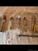 Full set of cutlery pieces arranged in rows, grouped by type and wrapped in plastic.