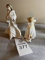 Photo of two Royal Doulton porcelain figurines, "Christmas Day" and "Sit," showing front and side views on a neutral background.