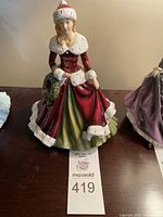 Front view of entire figurine showing red coat, green skirt and wreath