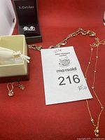 Photo shows two pairs of earrings and two necklaces arranged on a red background with auction lot card.