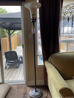 Full view of the floor lamp, showing the slag glass curved shade and metal stand in a living room.