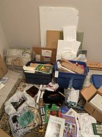 Overview of scrap glass pieces, two storage bins, pattern tubes, black tools bag and books scattered on floor