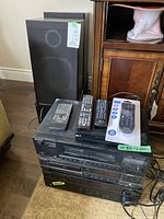 Photo showing all stacked stereo components including Yamaha receiver, Sony tape deck, Technics CD player and LG DVD/CD player with remote controls on top, and Kenwood speakers in background.