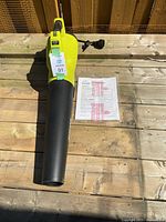 Sun Joe electric blower and manual on wooden deck, showing overall condition and color.