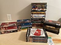 Photo of multiple DVDs arranged in stacks including Miss Marple, Poirot, Inspector Lewis, Sherlock Holmes, and other titles on a table against a wall.