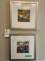 Two square framed abstract paintings stacked vertically on a wall. Frames are silver with white mats. Signature not readable.