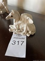 Side view showing the baby Pegasus lying down with wings partially open and detailed feather sculpting.