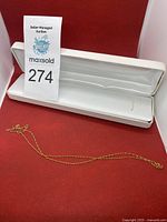 Chain displayed on red surface with white presentation case and lot tag