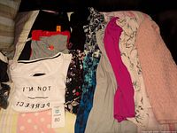 Folded assortment of 10 women's clothing items including tops, dresses, and a skirt, showing a range of colors and prints.