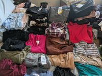 Photo showing an assortment of 18 pieces of women's clothing in various styles, colors, and brands, laid flat and partially stacked.