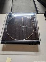 Full top view of the turntable with clear dust cover closed showing the Audio-Technica logo on the platter and the overall condition.