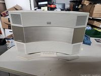 Front side view of the white Bose Acoustic Wave speaker unit, showing the speaker grille and base stand.