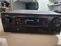 Front view of Denon AVR-1709 AV Receiver showing display screen and control knobs.