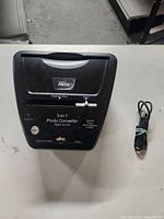 Top view of the black Digital Prism 3-in-1 Photo Converter device showing front controls and slot for negatives/slides.