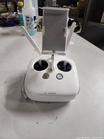 Front view of the DJI Phantom remote controller showing control sticks, power and function buttons, phone/tablet holder mount, and dual antennas.