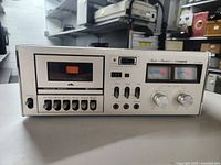 Front view of the Fisher Studio Standard CR-4025 cassette tape deck powered on with analog VU meters visible and control knobs and buttons on the front panel.