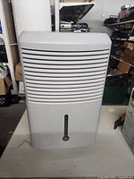 Front view of GE white dehumidifier showing air vent grille and water level indicator.