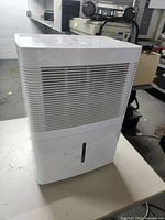 Front view of the white GE dehumidifier showing the vent grill on front and the bottom water level window.