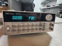 Front view showing display, function buttons, power button, rotary knob, and brand markings.