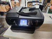 Front angle of HP Envy 7640 printer showing touchscreen display powered on with HP logo.