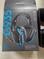 Box showing Logitech G935 headset with blue LED accents and features text about wireless 7.1 LIGHTSPEED gaming headset.