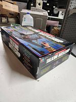 View of the original box standing on a table showing the Milton Bradley Electronic Talking Battleship packaging with some wear visible