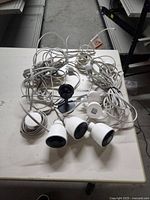 Four Nest security cameras with attached cables and mounts on white table.