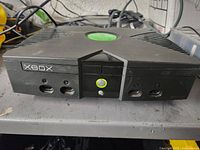 Front view of original Xbox console with four controller ports, power button with green ring, and disc drive closed.