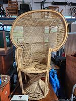 Front view of vintage rattan/wicker peacock chair showing large rounded fan backrest, circular seat, and woven base.
