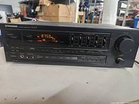 Front left angle view showing the front panel controls, digital display set to 87.50 MHz FM frequency, and model number SX-201.