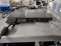 Sony PlayStation 2 Slim console showing front with two memory card slots and two controller ports open, plus USB and power indicator lights visible.