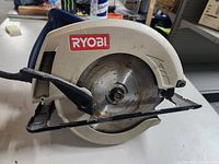 Side view of Ryobi 7 1/4 inch corded circular saw showing blade and blade guard with Ryobi logo.