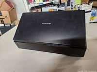 Closed view of a black ScanSnap scanner on a table showing the top surface with ScanSnap branding.