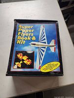 Closed box of Super Paper Flyers Book & Kit showing colorful paper planes on cover.