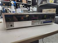 Front and side view of the Teac V-400X cassette deck showing power, timer, eject, and phones ports on the left side and cassette transport controls on the right.