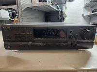 Front view of Technics SA-GX530 stereo receiver showing display, buttons, cassette deck, and volume knob.