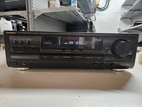 Front view of Technics stereo receiver powered on, displaying FM frequency 107.5, showing control buttons and volume knob.