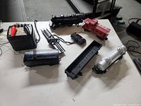 Wide view of all seven items including train cars, track, and transformer on floor