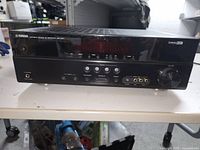 Front and top view of Yamaha Natural Sound AV Receiver powering on with control buttons and display visible.