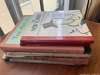 Stack of six New Yorker cartoon books with visible wear and vintage style covers on a windowsill.