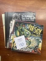 Top view of four Far Side comic books stacked on a wooden surface showing covers and edges.