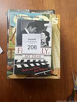 Four hardcover books stacked, visible titles include 'All-American Ads 1930s', 'Film Noir Compendium', and 'Frankly, My Dear' showing on the top with a black and white photo on the cover.