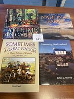 Four coffee table books arranged on a wooden table. Titles shown are related to Canada and its national parks and heritage.