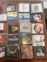 Overview of the collection of rock and pop CDs spread on a table showing album covers and jewel cases.
